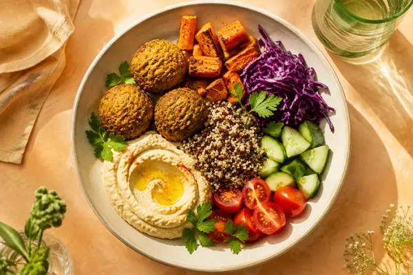 Falafel, hummus and colourful vegetables in a sunny bowl